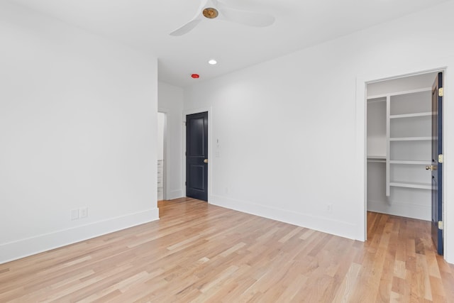 unfurnished bedroom with a closet, light hardwood / wood-style flooring, a spacious closet, and ceiling fan