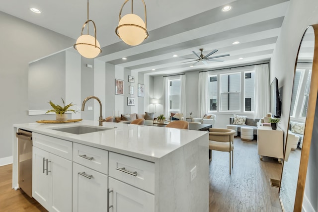 kitchen with an island with sink, sink, light hardwood / wood-style floors, white cabinetry, and hanging light fixtures