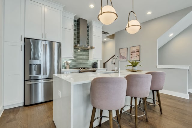 kitchen with a kitchen island with sink, stainless steel appliances, white cabinets, pendant lighting, and backsplash