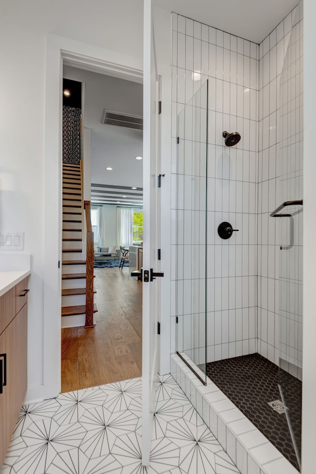 bathroom with a tile shower, vanity, and hardwood / wood-style floors