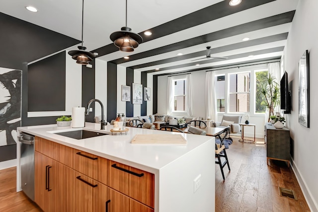 kitchen with dishwasher, light hardwood / wood-style flooring, a center island with sink, and sink