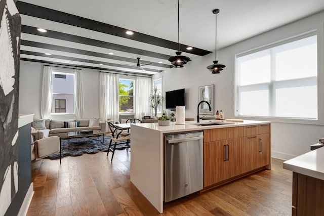 kitchen featuring light hardwood / wood-style flooring, a center island with sink, sink, dishwasher, and hanging light fixtures