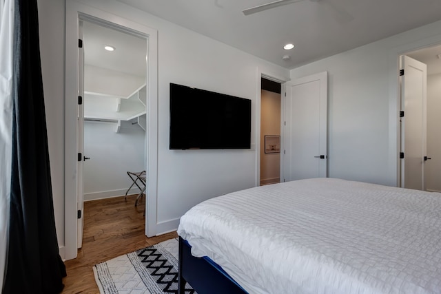 bedroom featuring ceiling fan, a closet, hardwood / wood-style floors, and a spacious closet