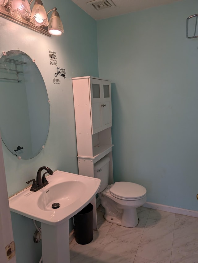 bathroom featuring toilet, marble finish floor, and visible vents