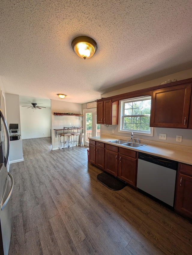 kitchen featuring a textured ceiling, dishwasher, a sink, and dark wood-style floors