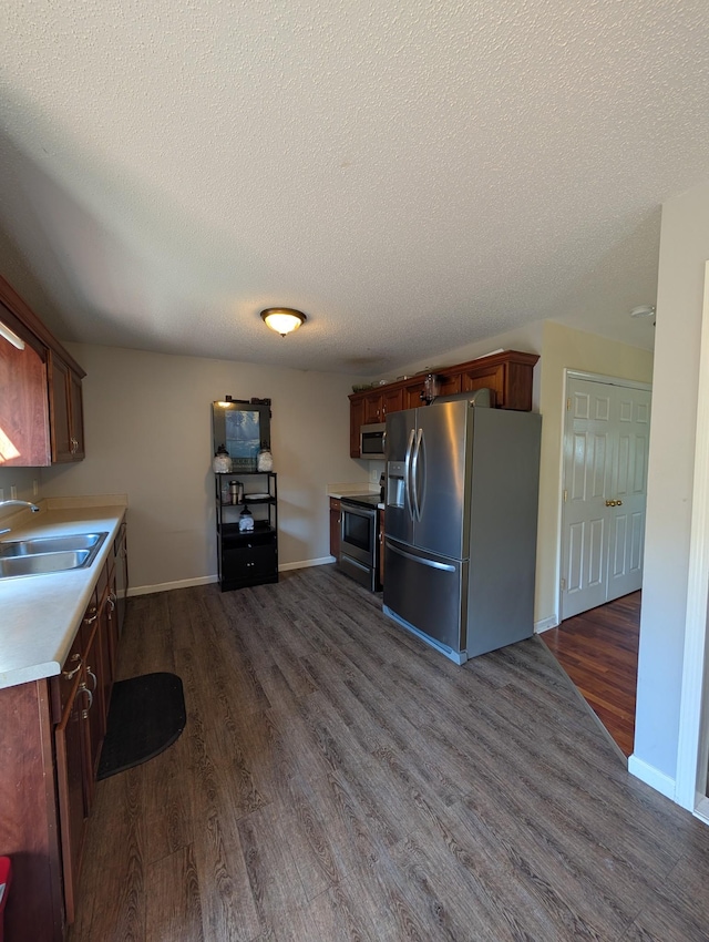 kitchen featuring a textured ceiling, dark wood-style flooring, a sink, and stainless steel appliances