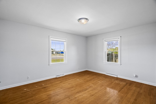 unfurnished room featuring a baseboard radiator and hardwood / wood-style floors