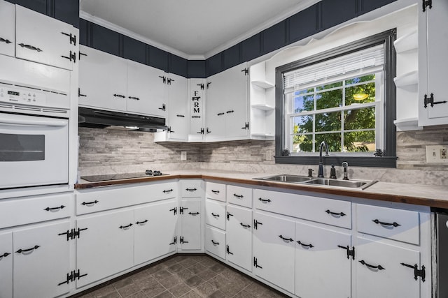 kitchen featuring tasteful backsplash, oven, sink, black electric cooktop, and white cabinets