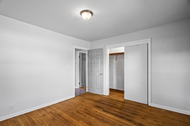 unfurnished bedroom with dark wood-type flooring and a closet