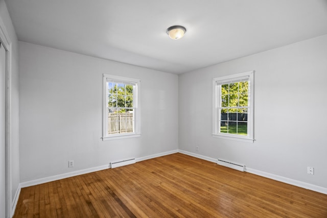 unfurnished room featuring a wealth of natural light, a baseboard radiator, and wood-type flooring