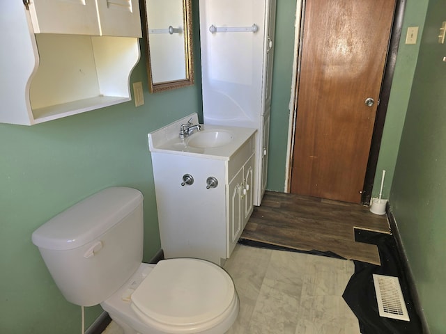 bathroom with toilet, vanity, and wood-type flooring