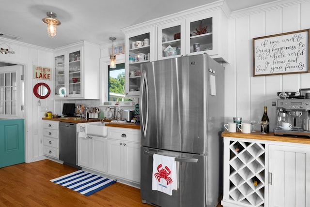 kitchen with wood counters, stainless steel appliances, white cabinets, and hanging light fixtures