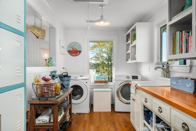 laundry area with cabinets, sink, washer and dryer, ornamental molding, and light hardwood / wood-style floors