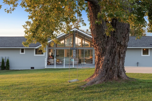 rear view of house featuring a sunroom and a lawn