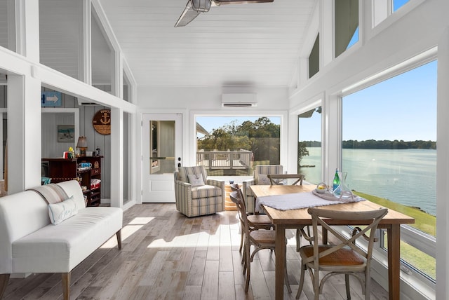 sunroom featuring a water view, an AC wall unit, and lofted ceiling