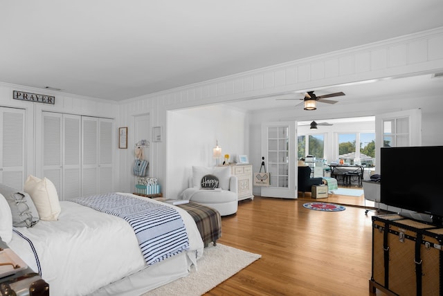 bedroom featuring ceiling fan, wood-type flooring, ornamental molding, and french doors