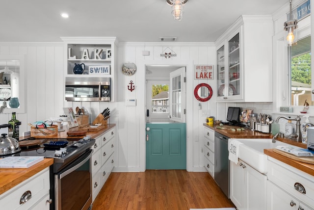 kitchen with stainless steel appliances, crown molding, pendant lighting, light hardwood / wood-style floors, and white cabinetry