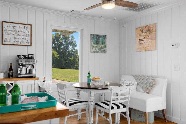 interior space featuring breakfast area, ceiling fan, crown molding, hardwood / wood-style flooring, and wood walls