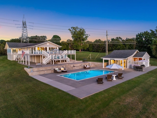 pool at dusk with a patio area, a bar, a yard, and a deck