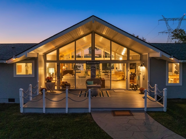 back house at dusk featuring a deck and a yard