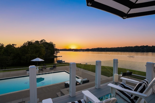 pool at dusk featuring a water view