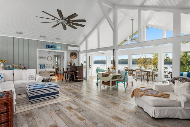 living room featuring a healthy amount of sunlight, a water view, high vaulted ceiling, and light hardwood / wood-style flooring