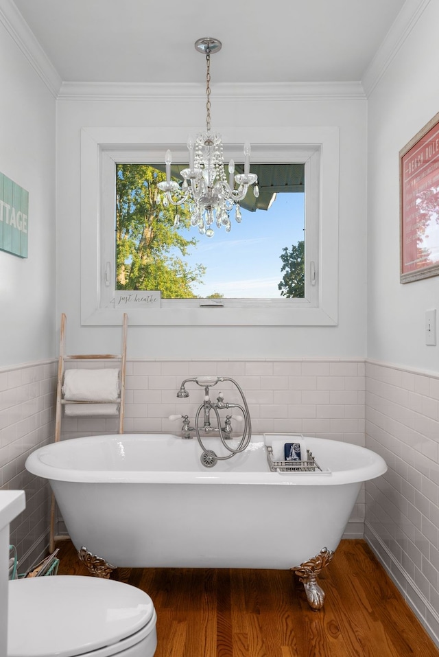 bathroom with a washtub, hardwood / wood-style flooring, tile walls, and ornamental molding