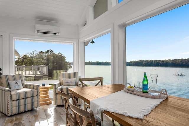 sunroom with a wall mounted air conditioner, a water view, lofted ceiling, and a wealth of natural light