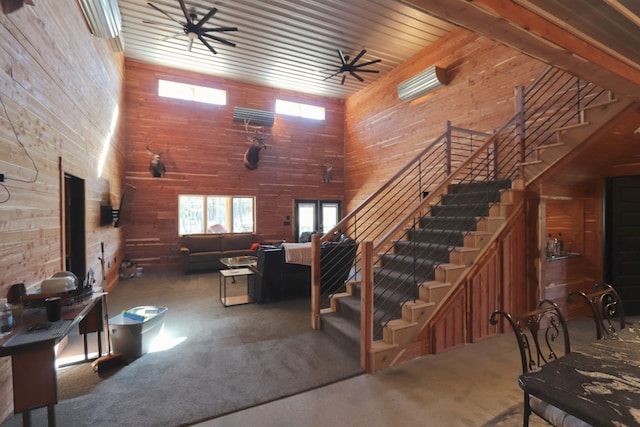 carpeted living room featuring wooden walls and a towering ceiling