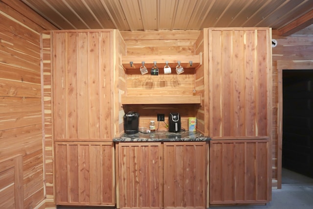 bar with light brown cabinetry, wood walls, and wooden ceiling