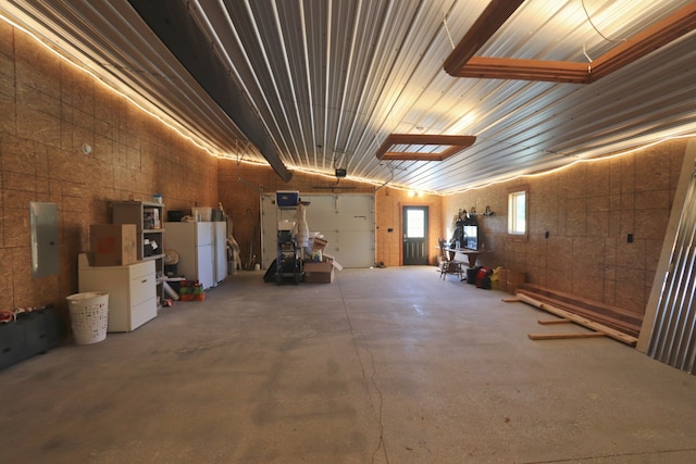 garage featuring electric panel and white fridge