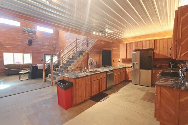 kitchen featuring wood walls, a kitchen island, dark stone countertops, sink, and stainless steel appliances