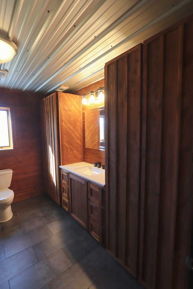 bathroom with wooden walls, vanity, and toilet