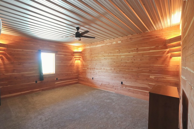 carpeted empty room featuring ceiling fan, wooden walls, and wood ceiling