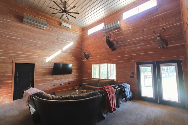 living room featuring ceiling fan, wood ceiling, wooden walls, carpet, and a high ceiling