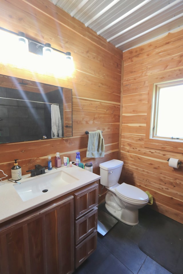 bathroom featuring wooden walls, tile patterned floors, vanity, and toilet