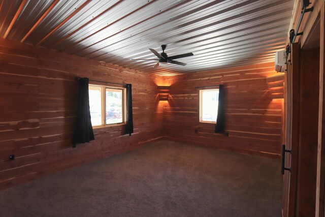 carpeted empty room featuring ceiling fan and wood walls