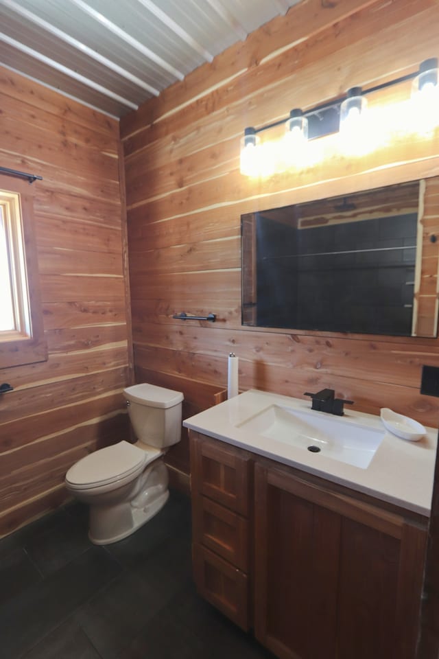 bathroom with wooden walls, toilet, and vanity