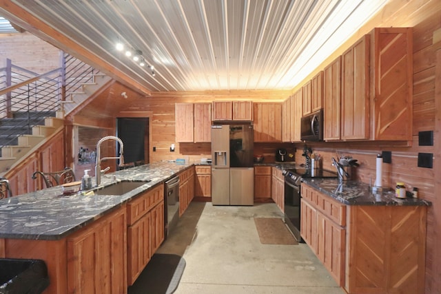 kitchen with wood walls, dark stone countertops, a large island, and black appliances