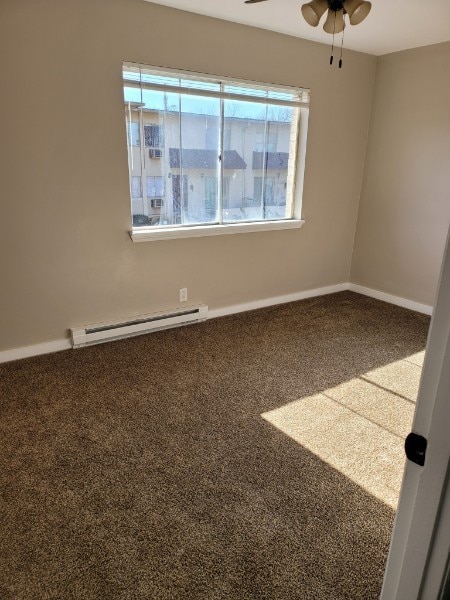 carpeted empty room featuring ceiling fan and a baseboard radiator