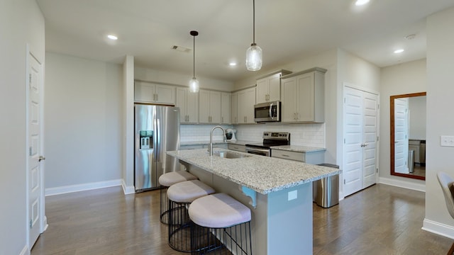 kitchen featuring light stone counters, sink, decorative light fixtures, stainless steel appliances, and dark hardwood / wood-style flooring