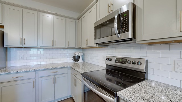 kitchen featuring light stone countertops, appliances with stainless steel finishes, and decorative backsplash