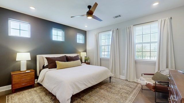 bedroom featuring ceiling fan, dark hardwood / wood-style floors, and multiple windows