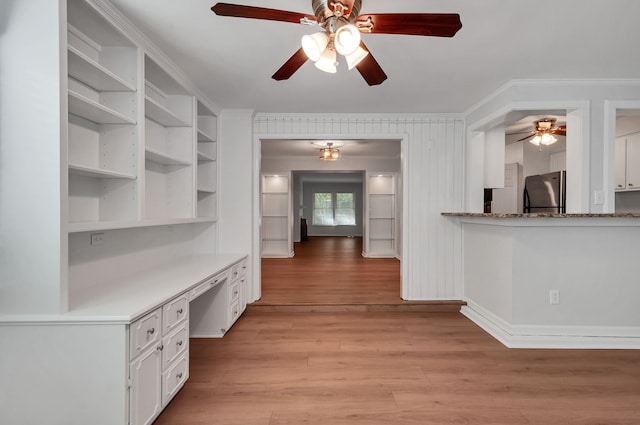 kitchen featuring built in desk, stainless steel refrigerator, white cabinetry, light hardwood / wood-style flooring, and ornamental molding