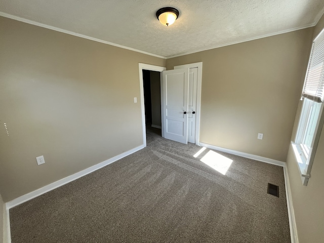 carpeted empty room featuring ornamental molding and a textured ceiling