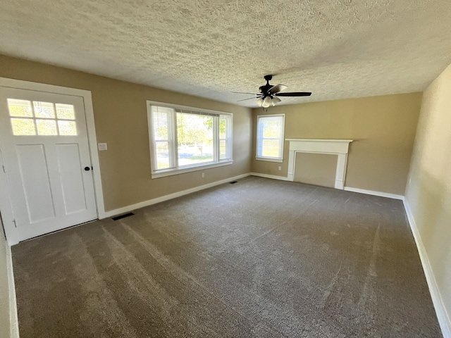 unfurnished living room featuring ceiling fan, a textured ceiling, and dark colored carpet