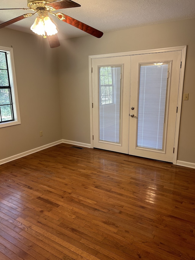 empty room with ceiling fan, french doors, dark hardwood / wood-style floors, and a healthy amount of sunlight