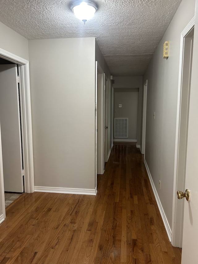 corridor featuring a textured ceiling and dark wood-type flooring