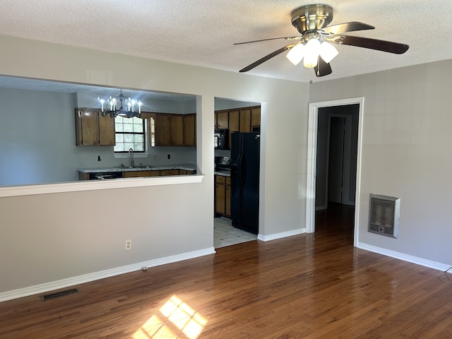 kitchen featuring wood-type flooring, ceiling fan with notable chandelier, heating unit, black appliances, and a textured ceiling