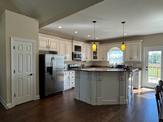 kitchen featuring decorative light fixtures, stainless steel appliances, white cabinetry, and a kitchen island